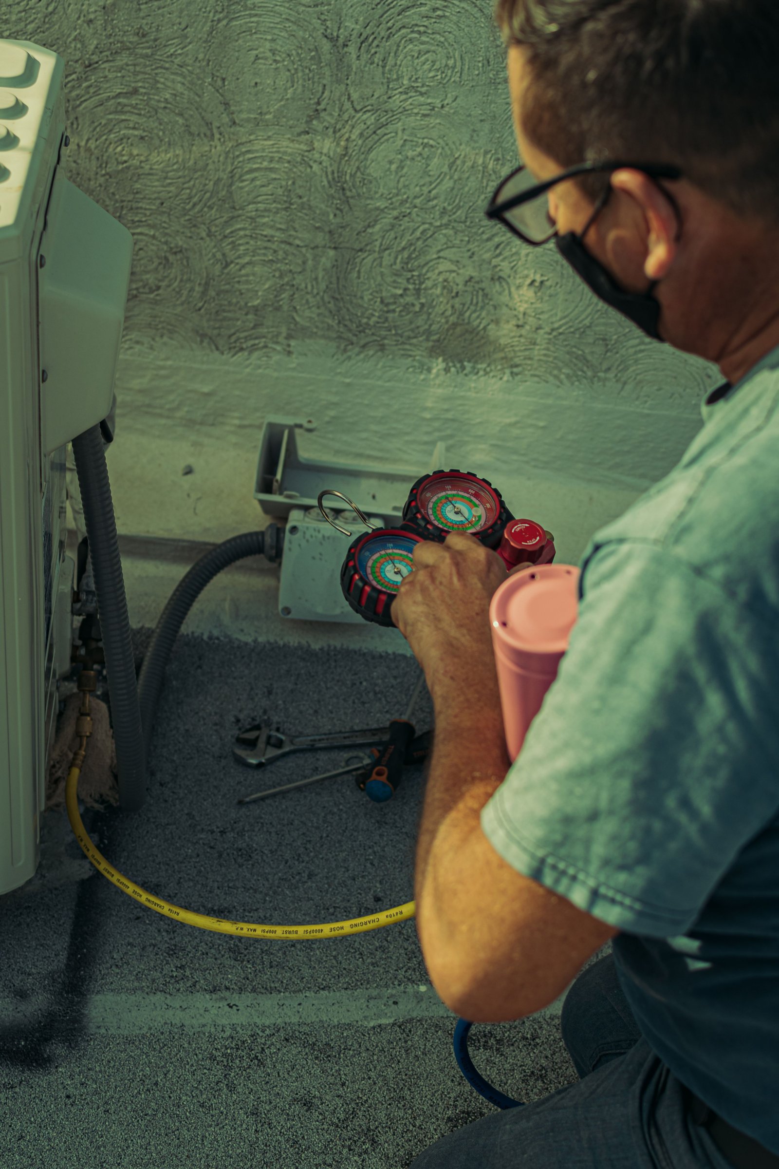 HVAC technician checking equipment with gauges for a maintenance page